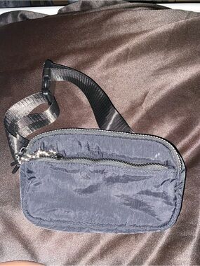 Black nylon belt bag featuring an adjustable strap